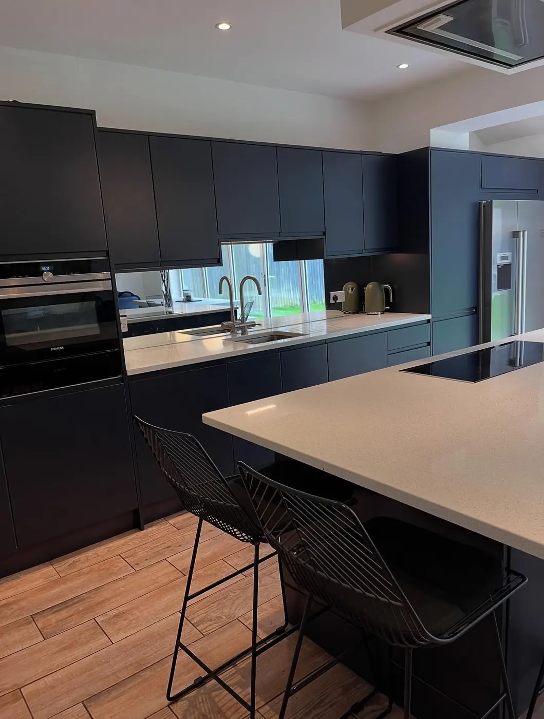 Navy handleless kitchen with island and mirrored splashback