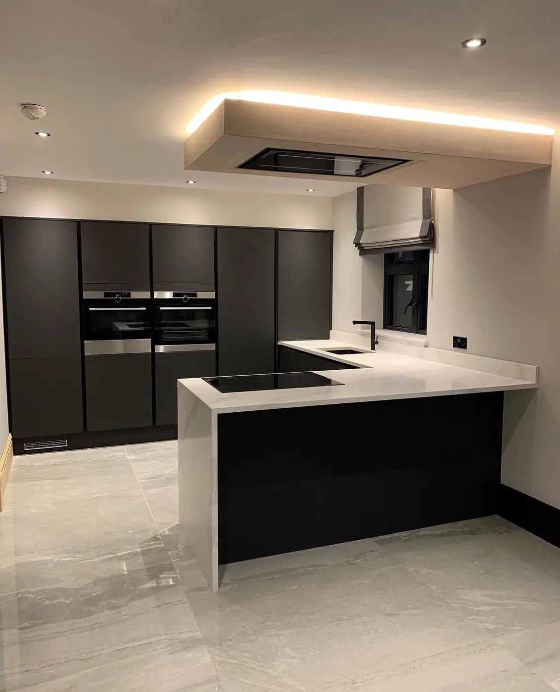Black handleless kitchen with ceiling extractor and lit bulkhead
